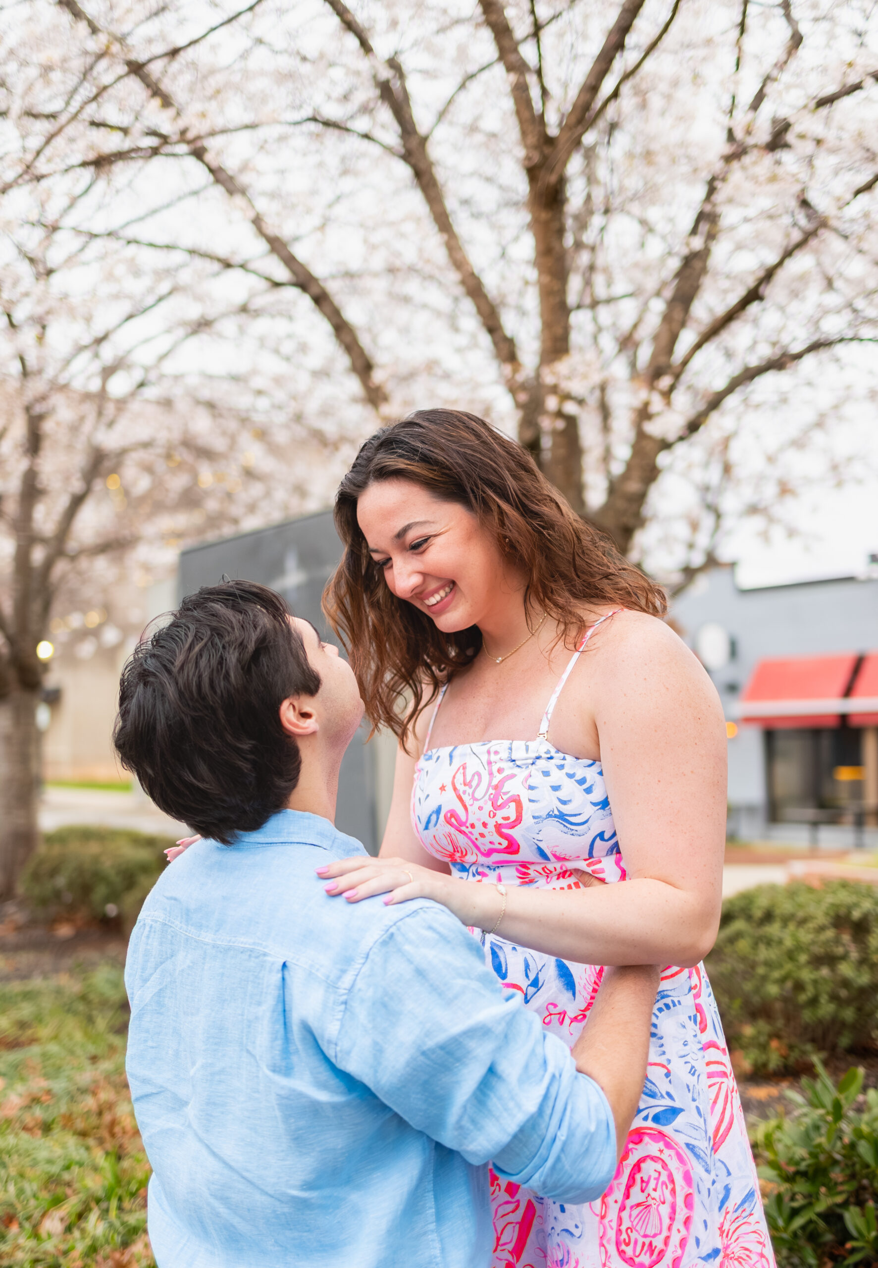 couple on main street in downtown greenville hugging under blossom trees