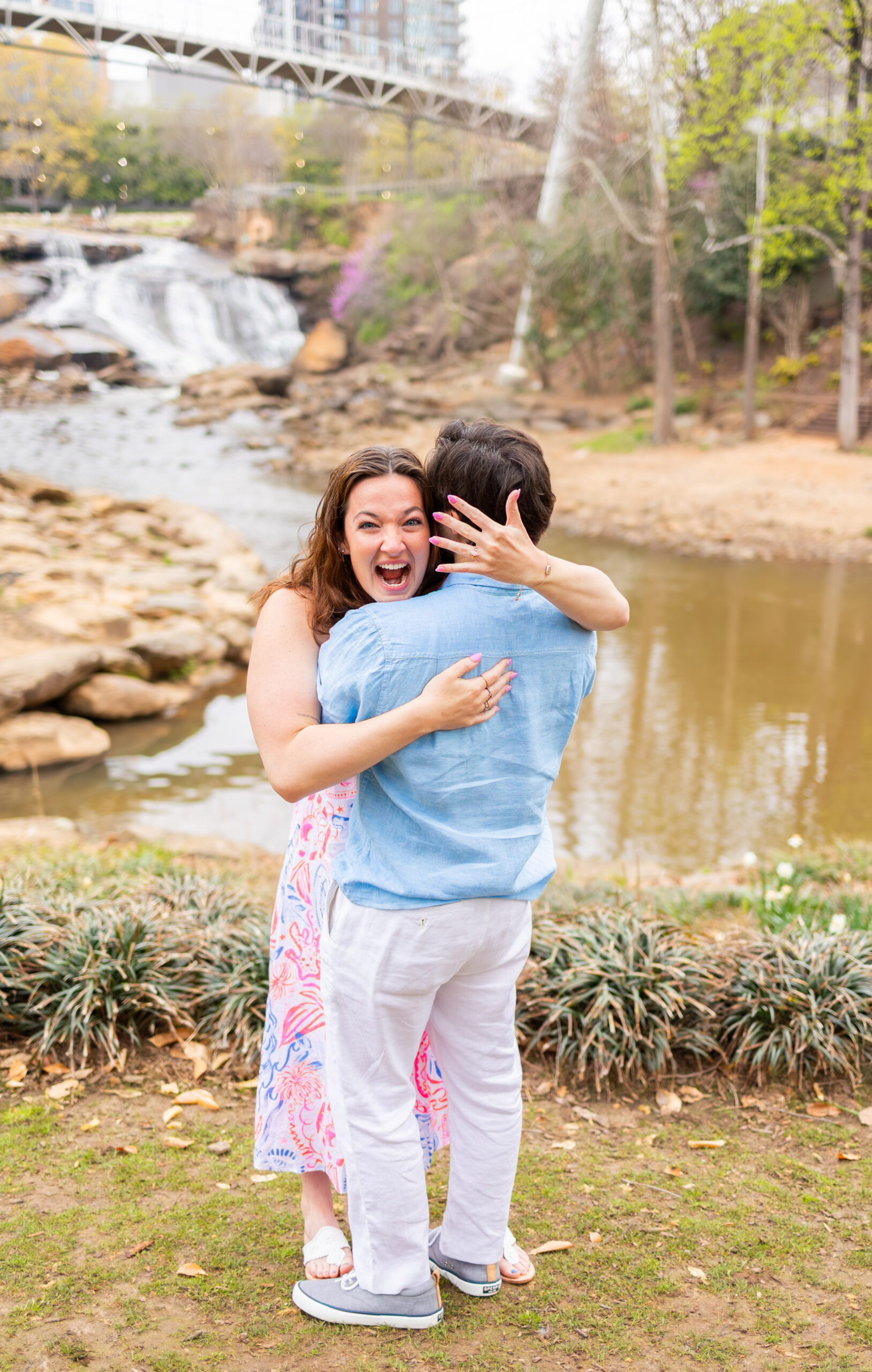girl showing off engagement ring after proposal in downtown greenville in front of river
