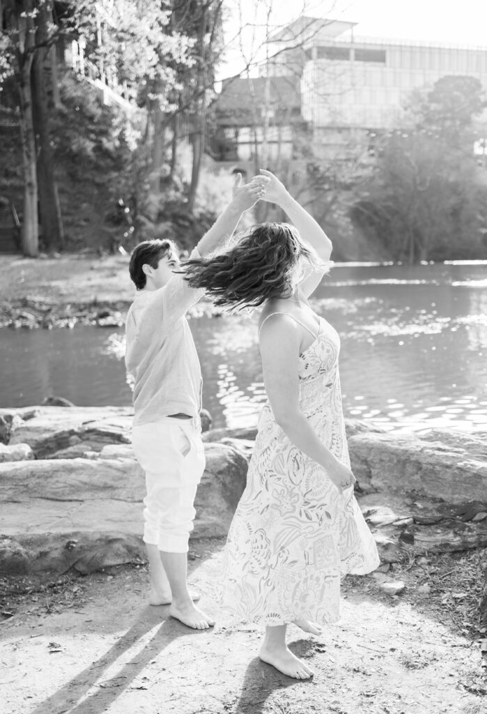 black and white image of guy spinning girl in front of calm river in greenville sc