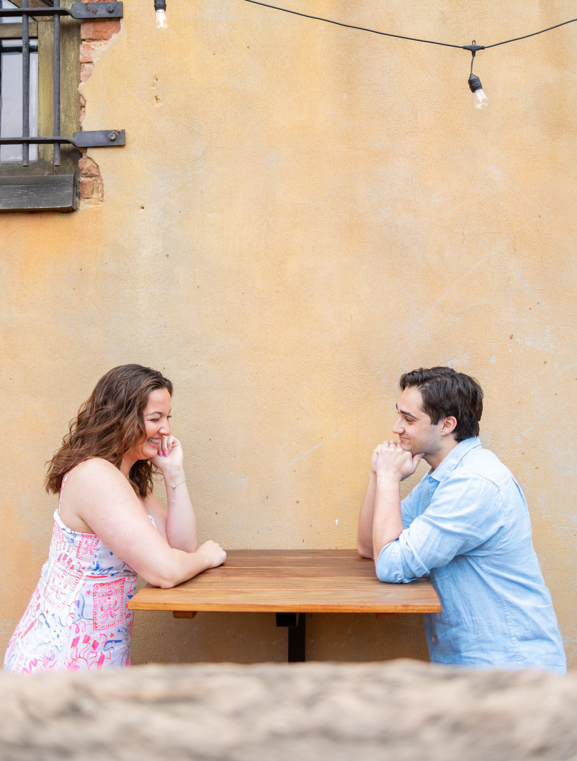 couple sitting across from each other at outdoors table and laughing