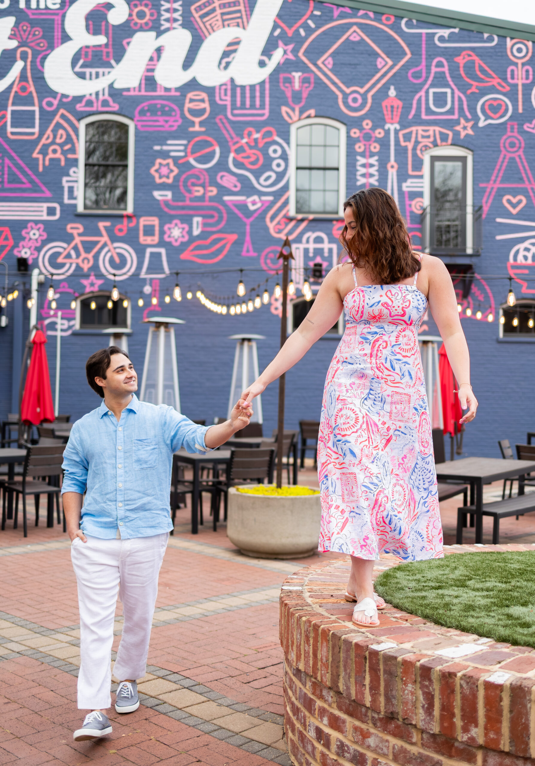 couple walking through square of artistic district in greenville, holding hands
